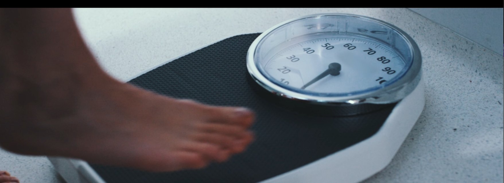 A foot stepping onto a bathroom scale